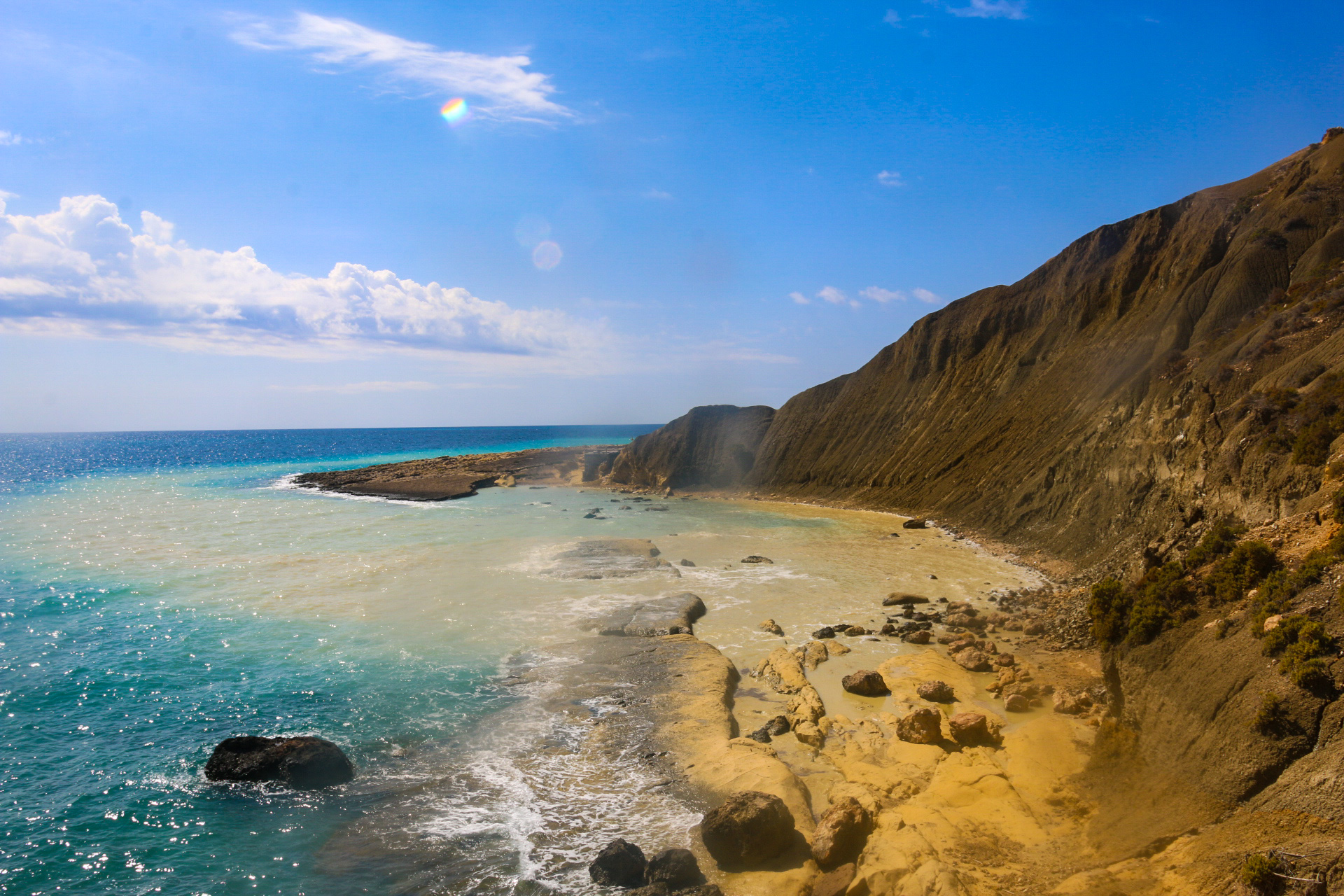 Gozo's dramatic south coast — golden clay cliffs meeting turquoise Mediterranean water, the kind of raw coastline you won't find on any tourist brochure
