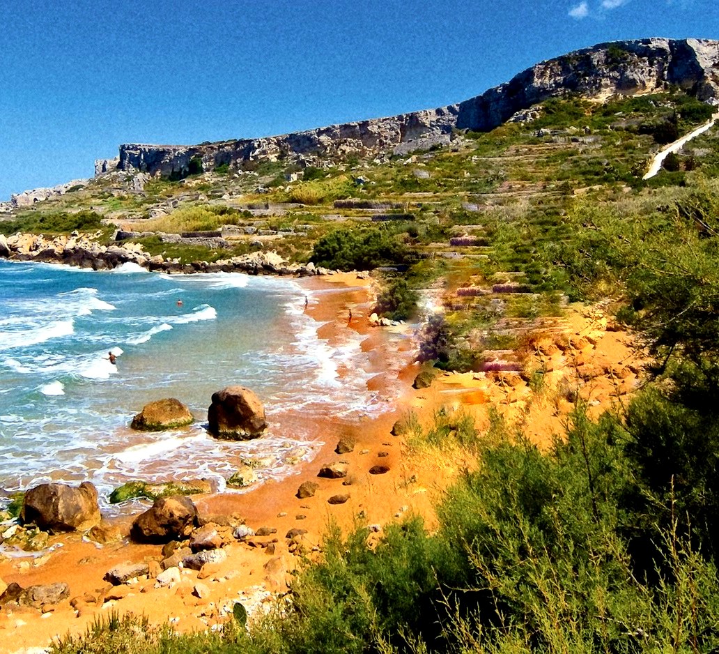 San Blas Bay in Gozo — red-orange sand, turquoise waves, and terraced cliffs with barely a soul in sight